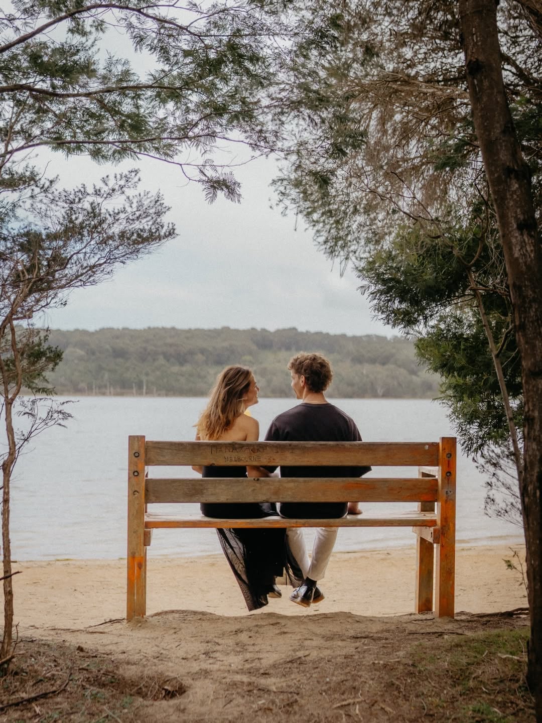 Sophie and Alex on a wooden bench looking out over the lake
